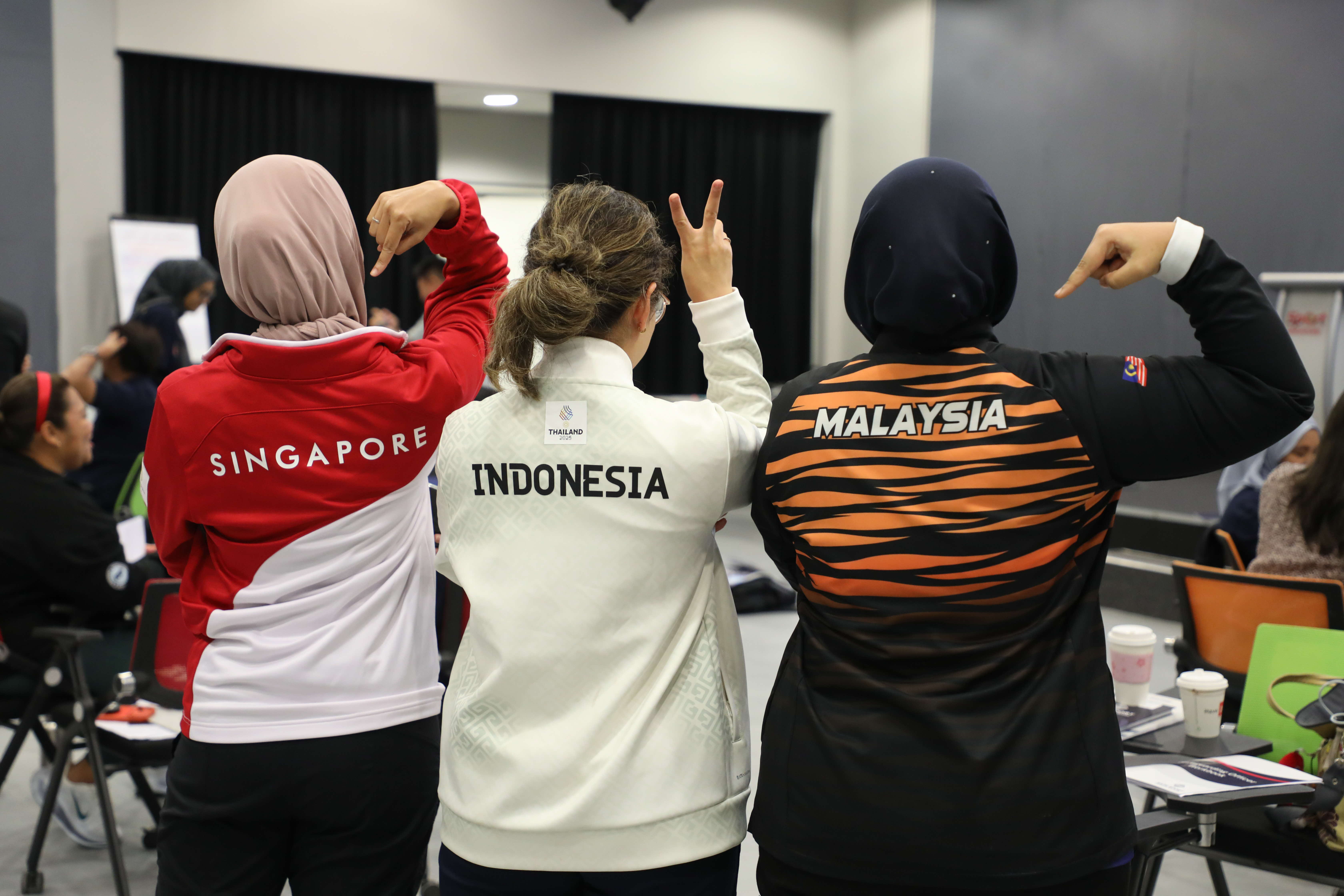3 women wearing jackets from different countries posing together